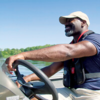Boat and water safety A person wearing a life jacket, safely opperates a boat on a lake.