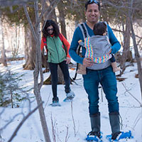 Family snowshoeing through the woods