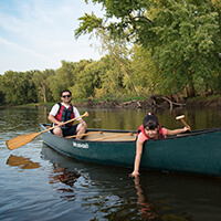 Two people in a canoe paddling on a river.