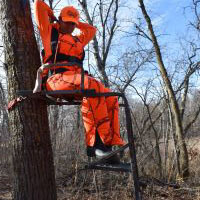 person wearing orange sitting in a tree stand