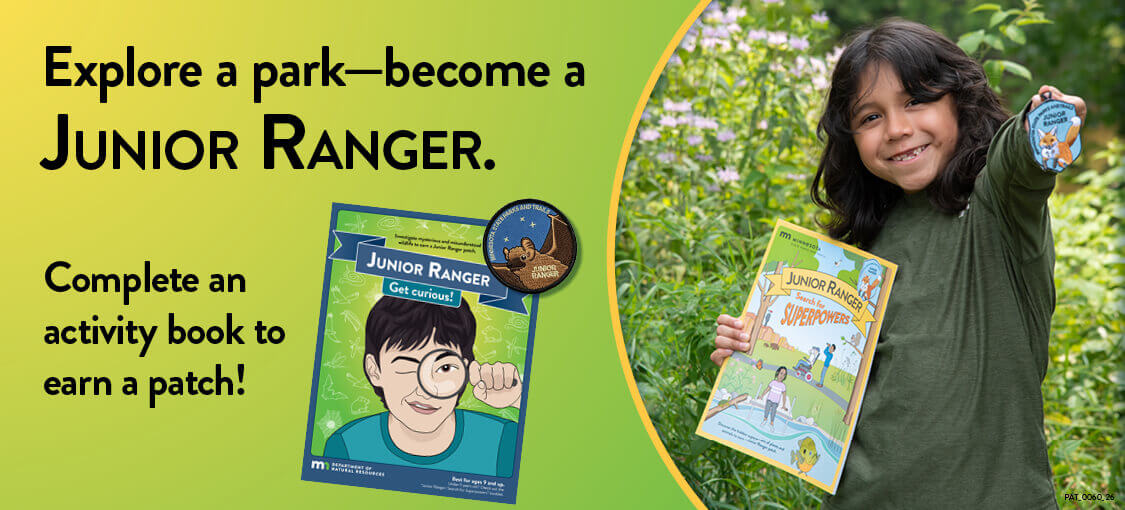 Explore a park, become a Junior Ranger. Complete an activity book to earn a patch. A child (outdoors) carries an activity book and holds up a patch.